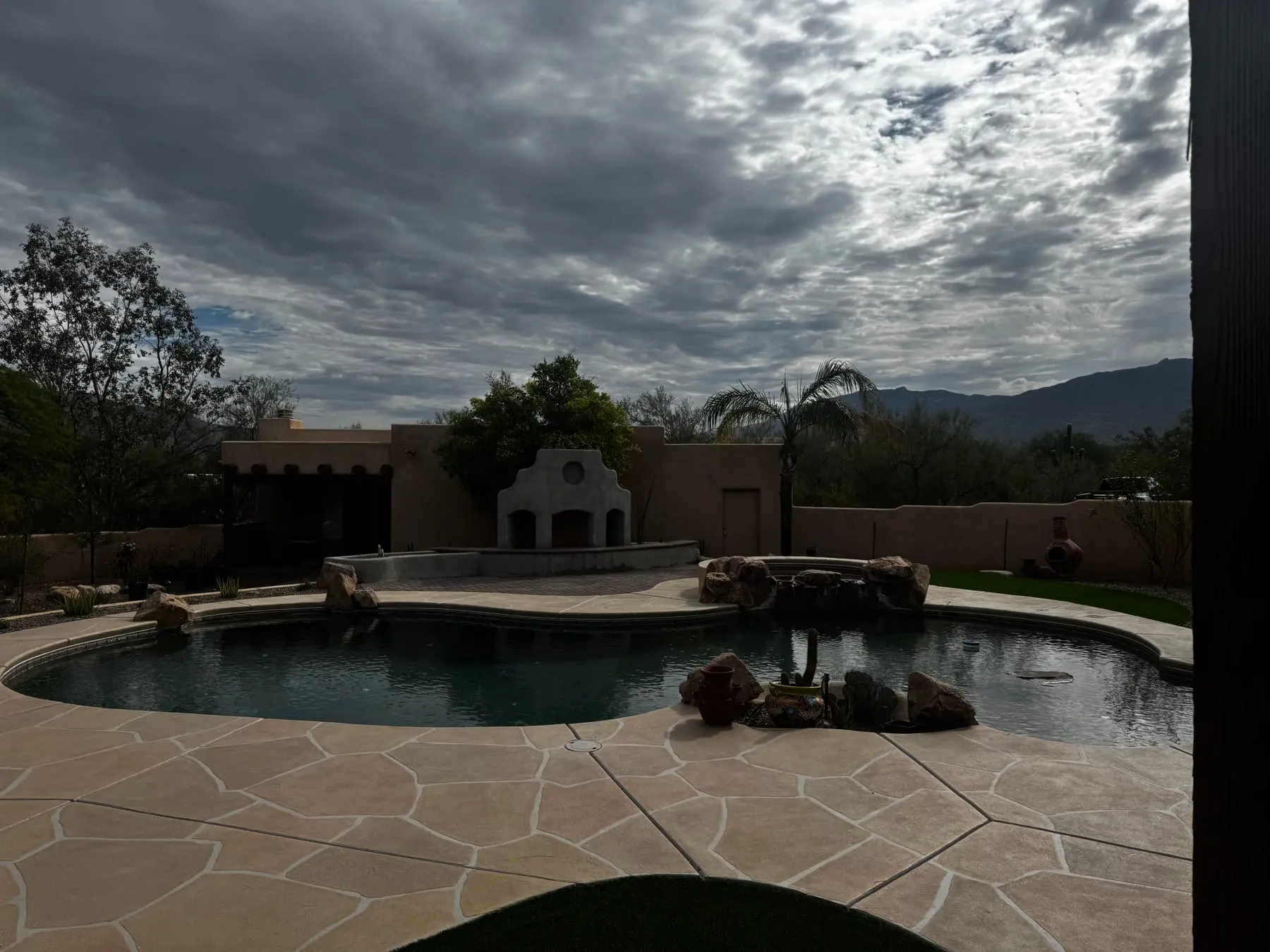 Backyard view across an existing pool to the new outdoor fireplace and seat wall, east Tucson, AZ.