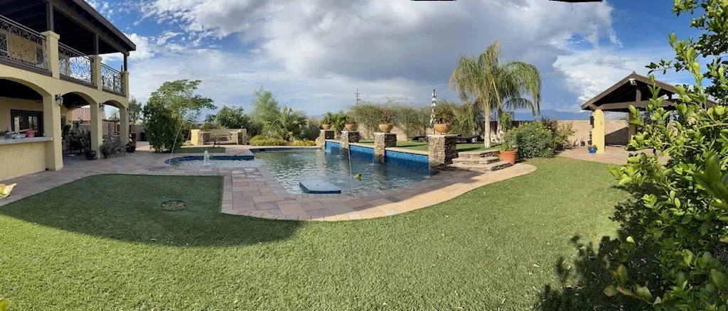 Wide backyard with a pool, spa, ramada and lawn on a large desert lot