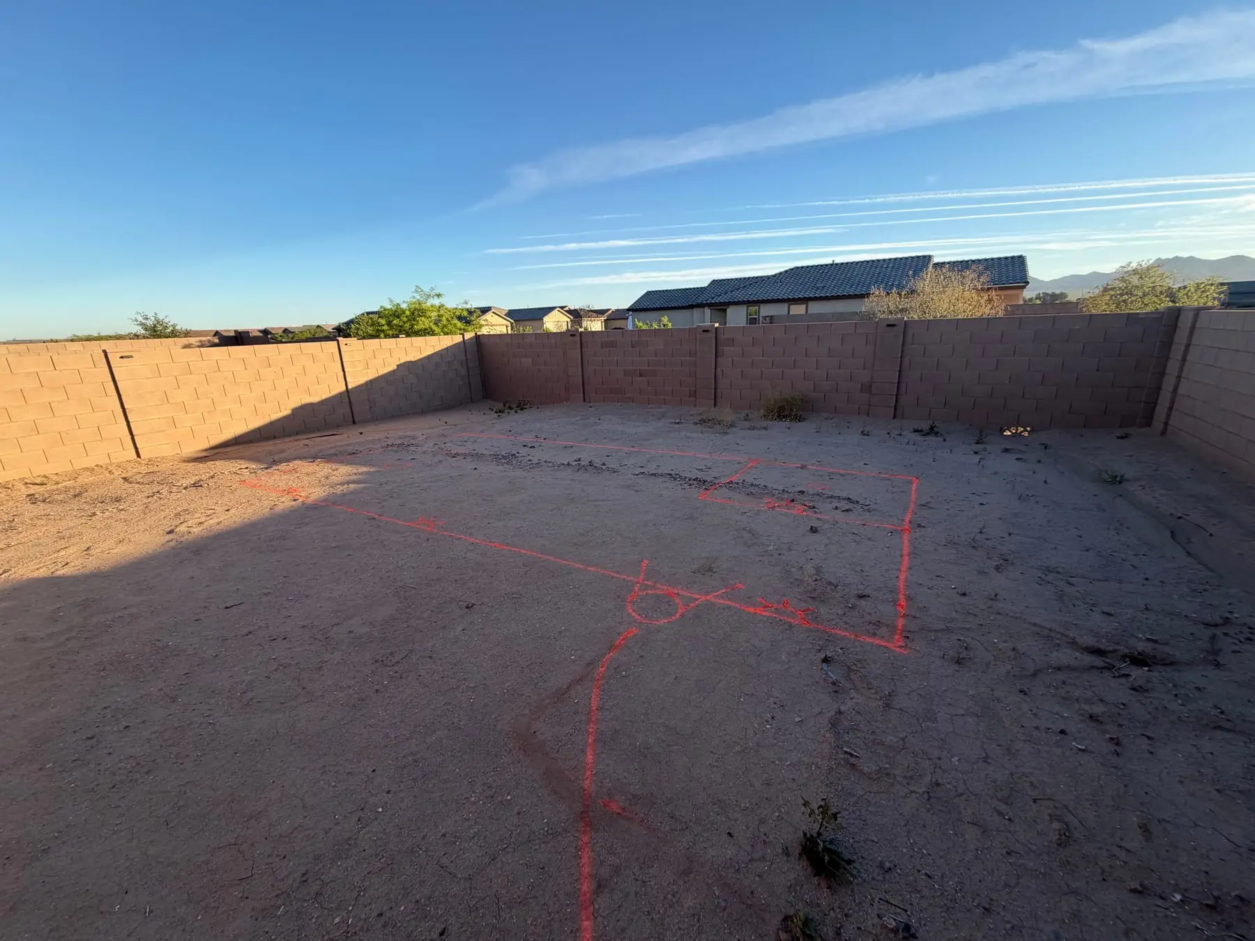 Pool and spa outline marked in orange paint on a bare backyard in Gladden Farms.