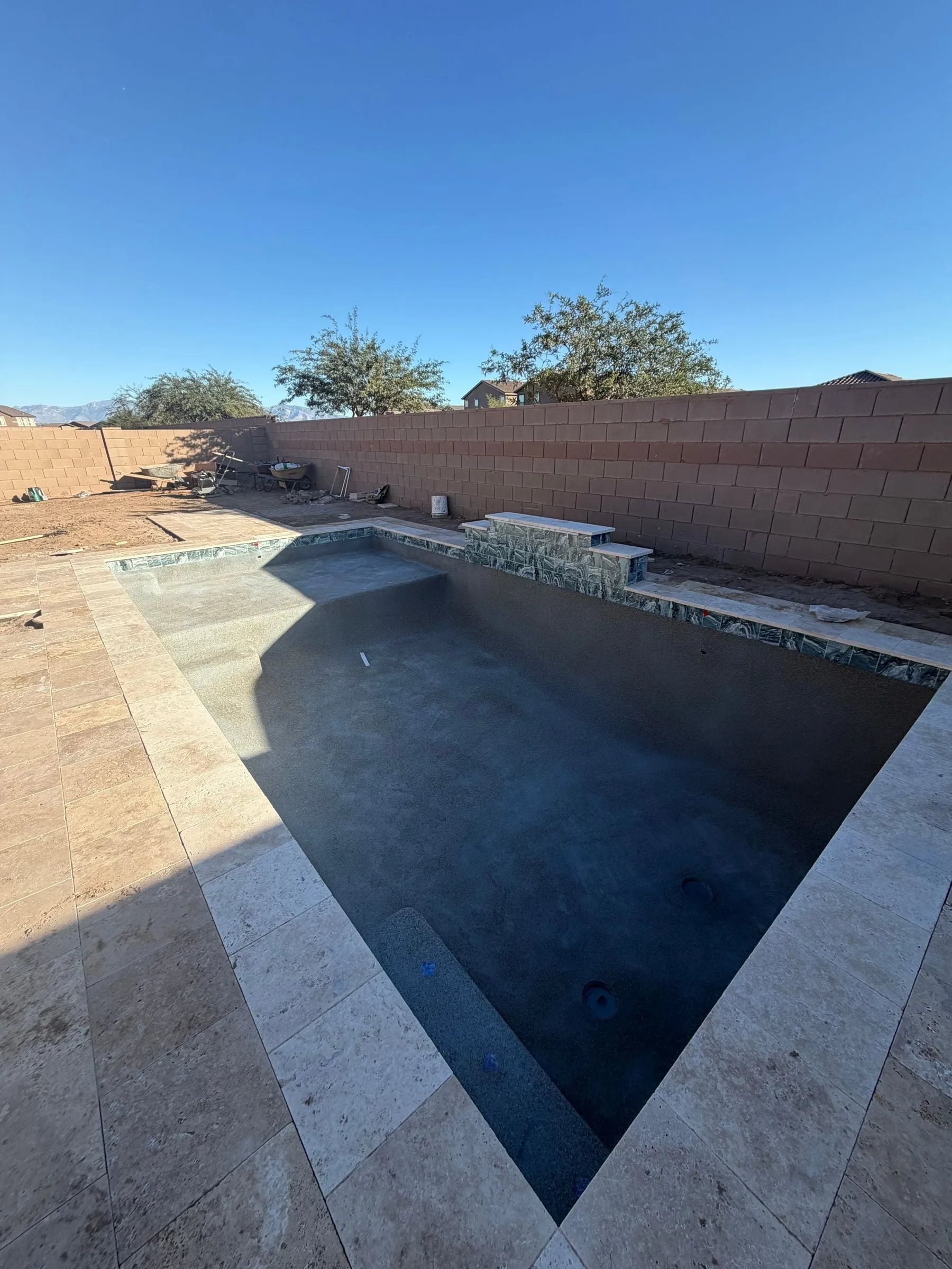 Newly finished dark pool beginning to fill, framed by a travertine deck.