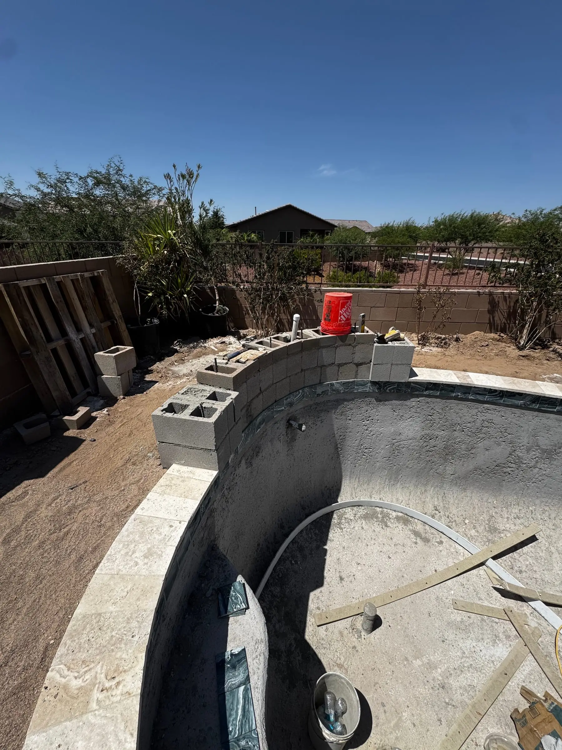 Curved coping set on a freeform pool shell, with block for the raised wall at the back, Marana, AZ.