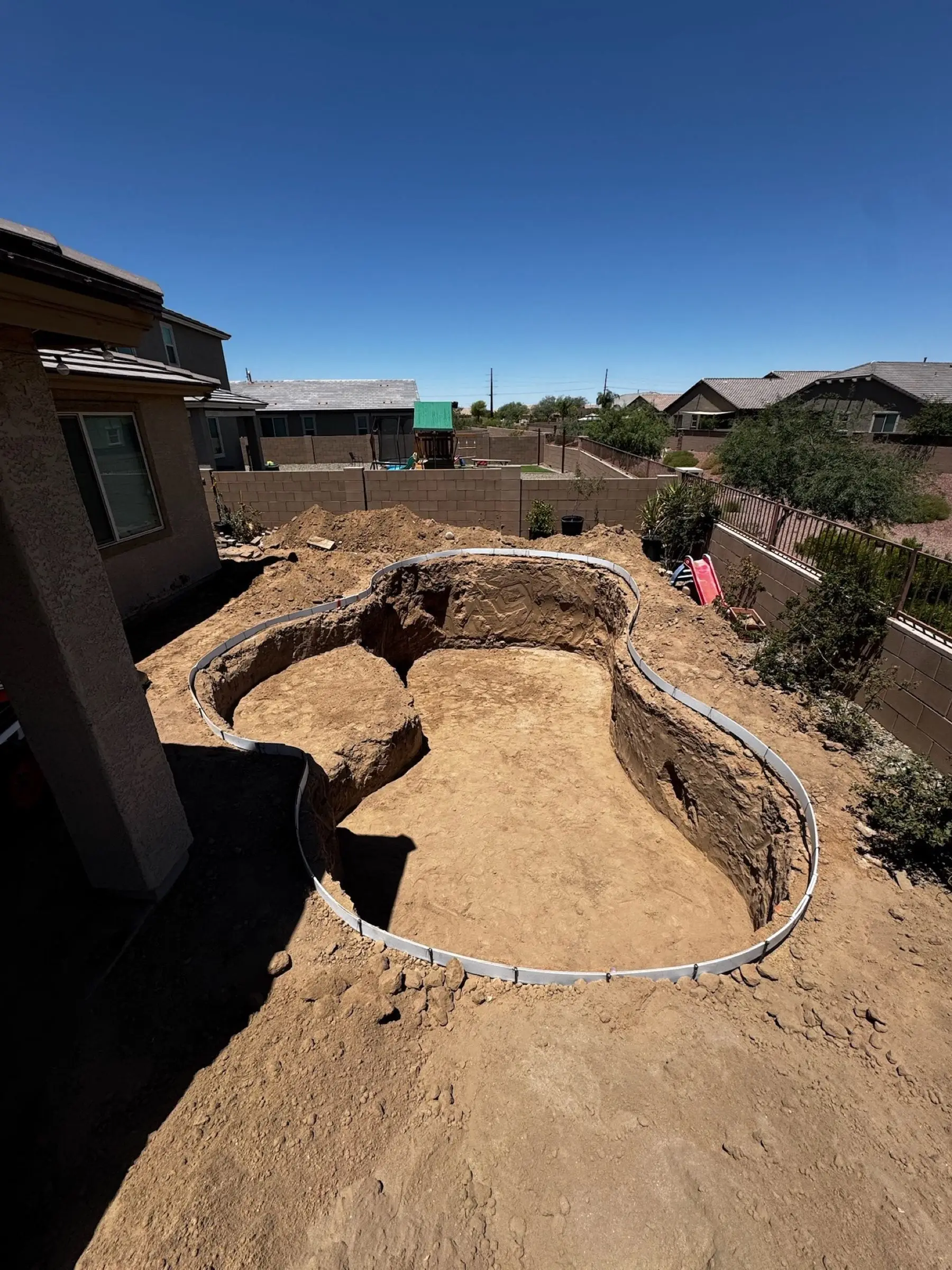 Freeform pool excavation with curved forms set along the edge of the dig, Marana, AZ.