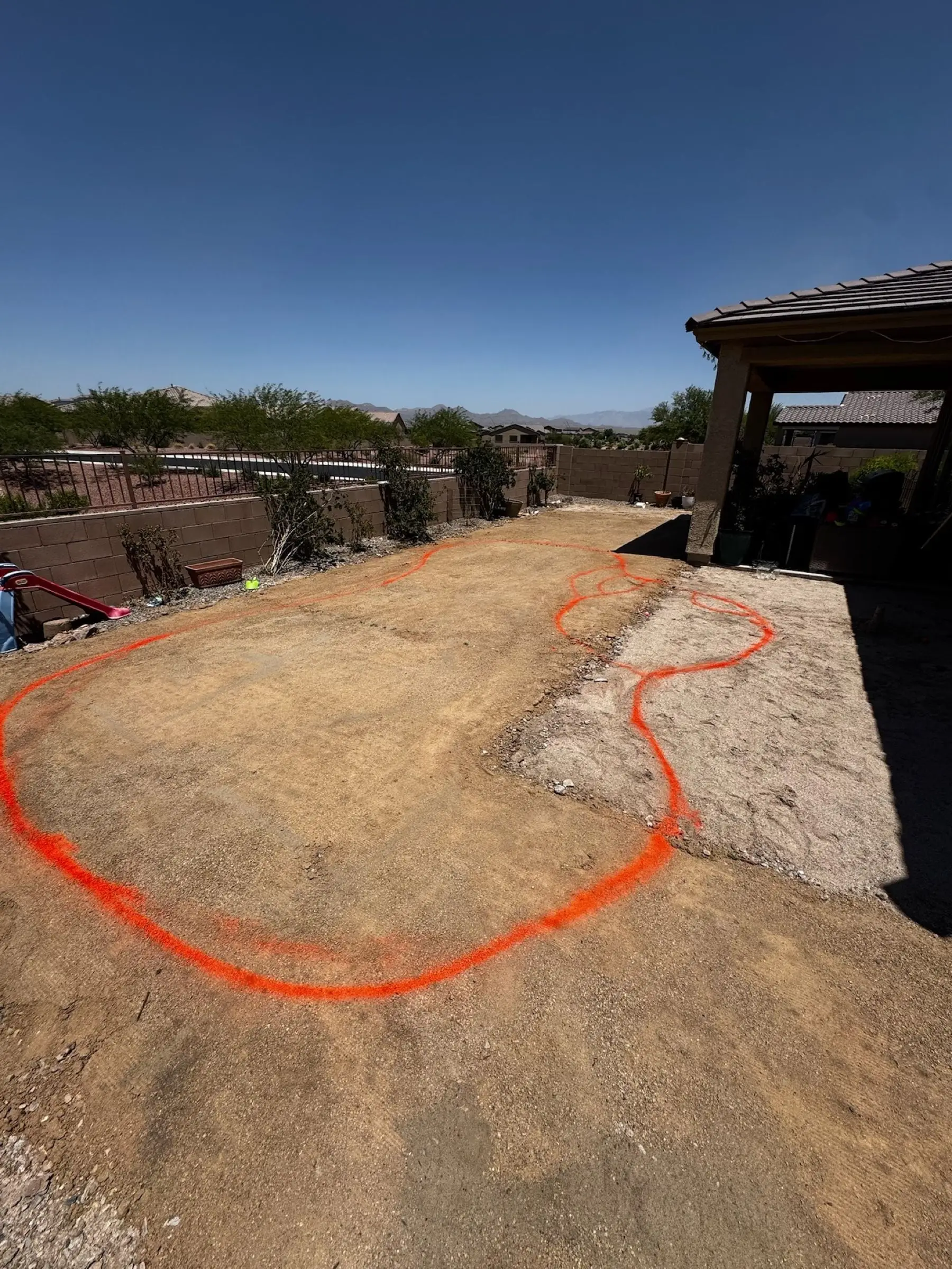 Orange paint marks a freeform pool outline in a Marana backyard before excavation.