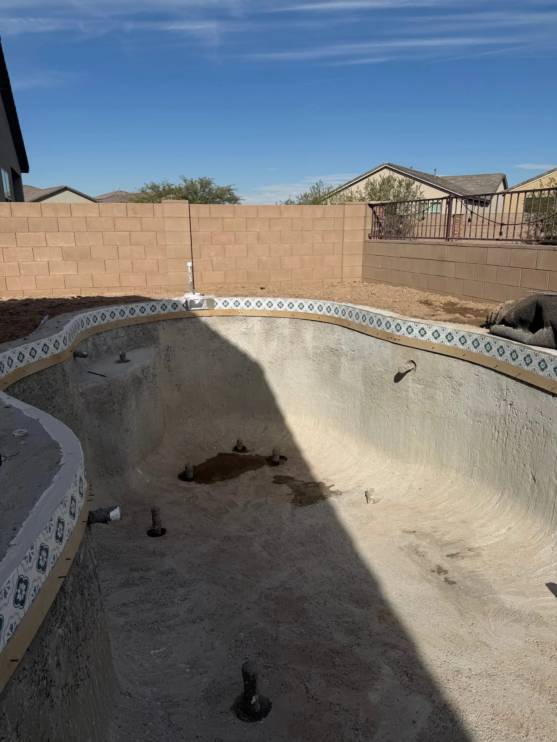 Freeform pool shell with a patterned waterline tile band set.