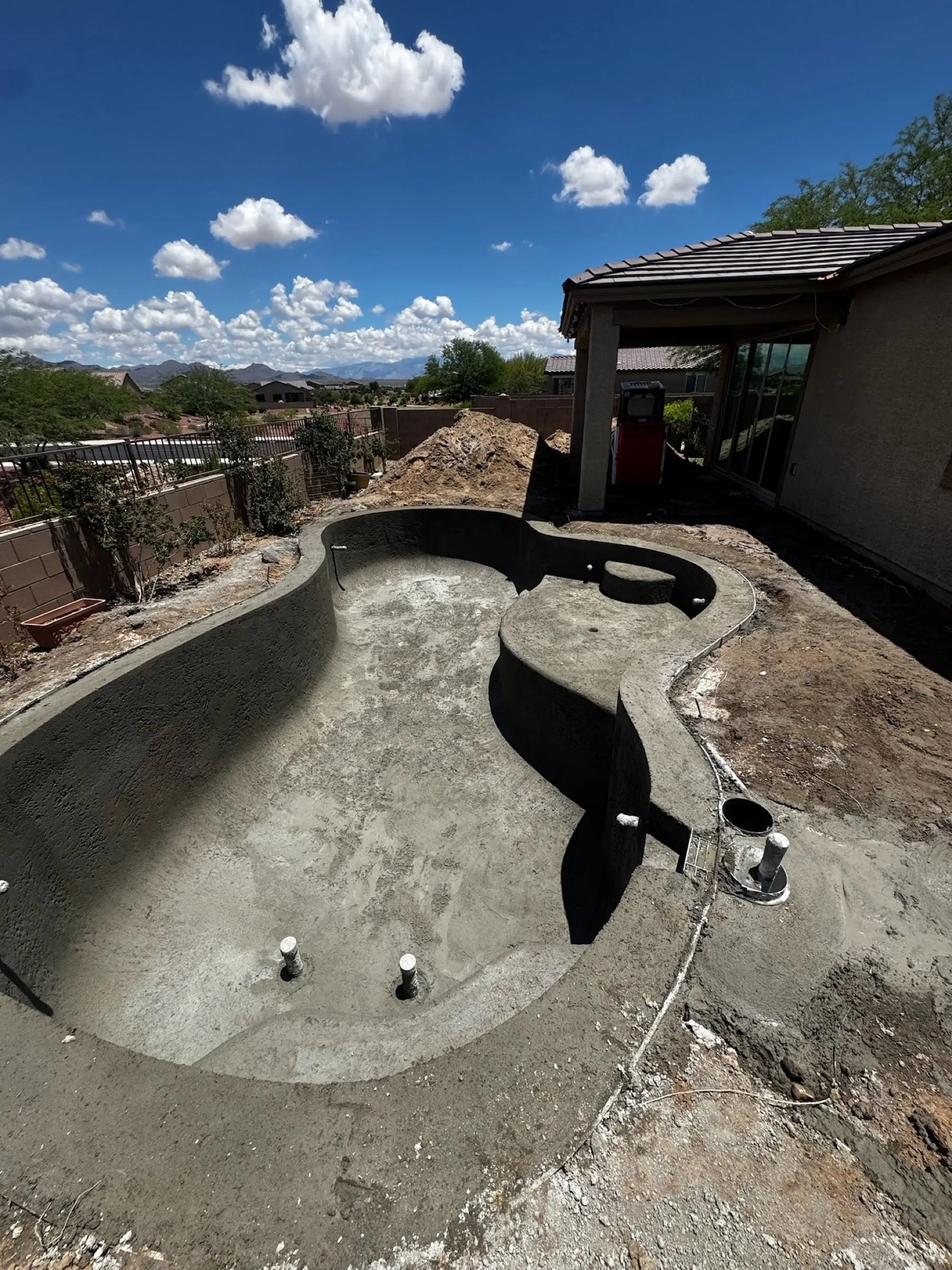 Freeform pool shell after shotcrete, showing its curved walls and sweeping entry step, Marana, AZ.