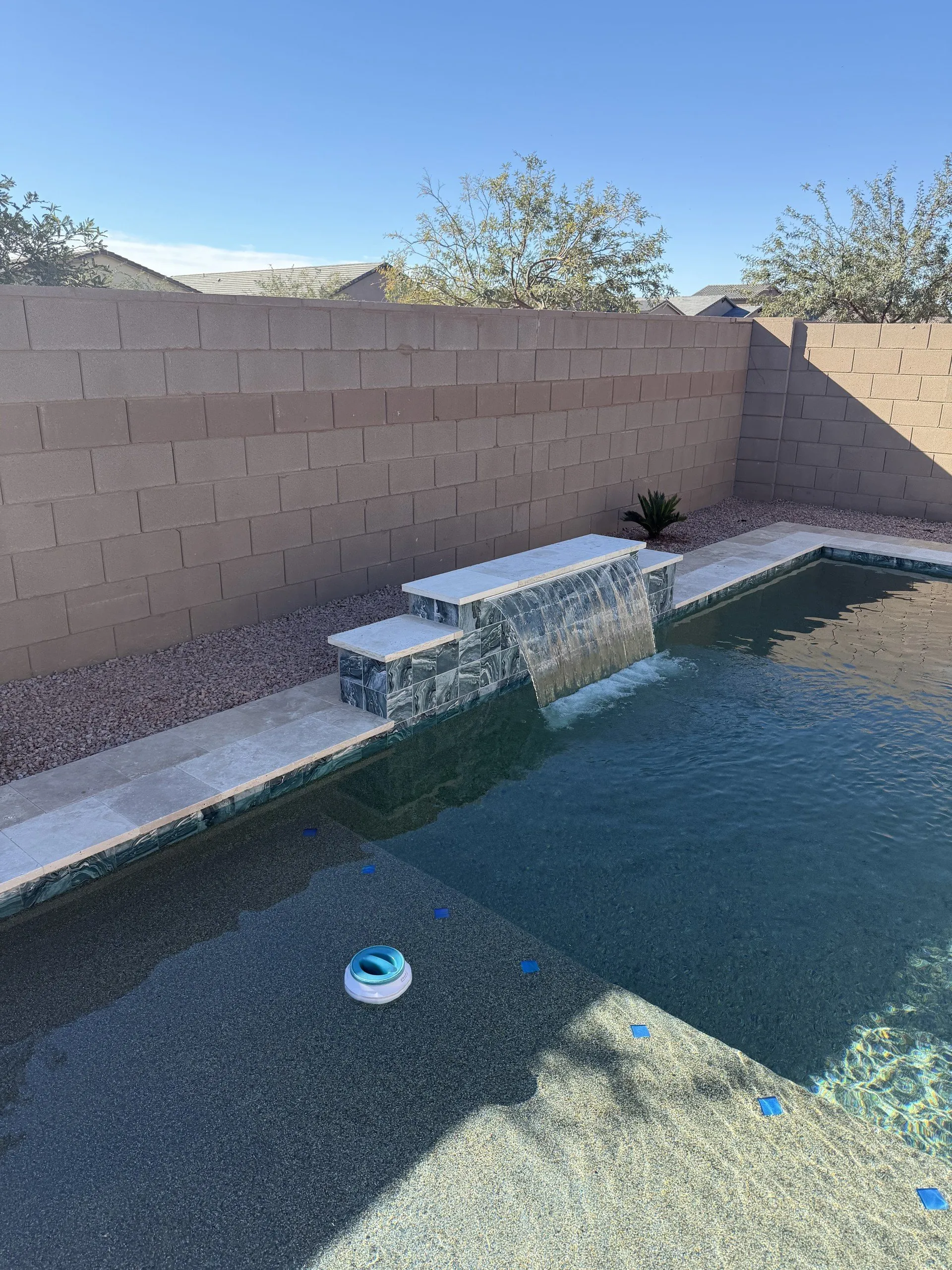 Geometric pool with sheer descent water feature and travertine coping