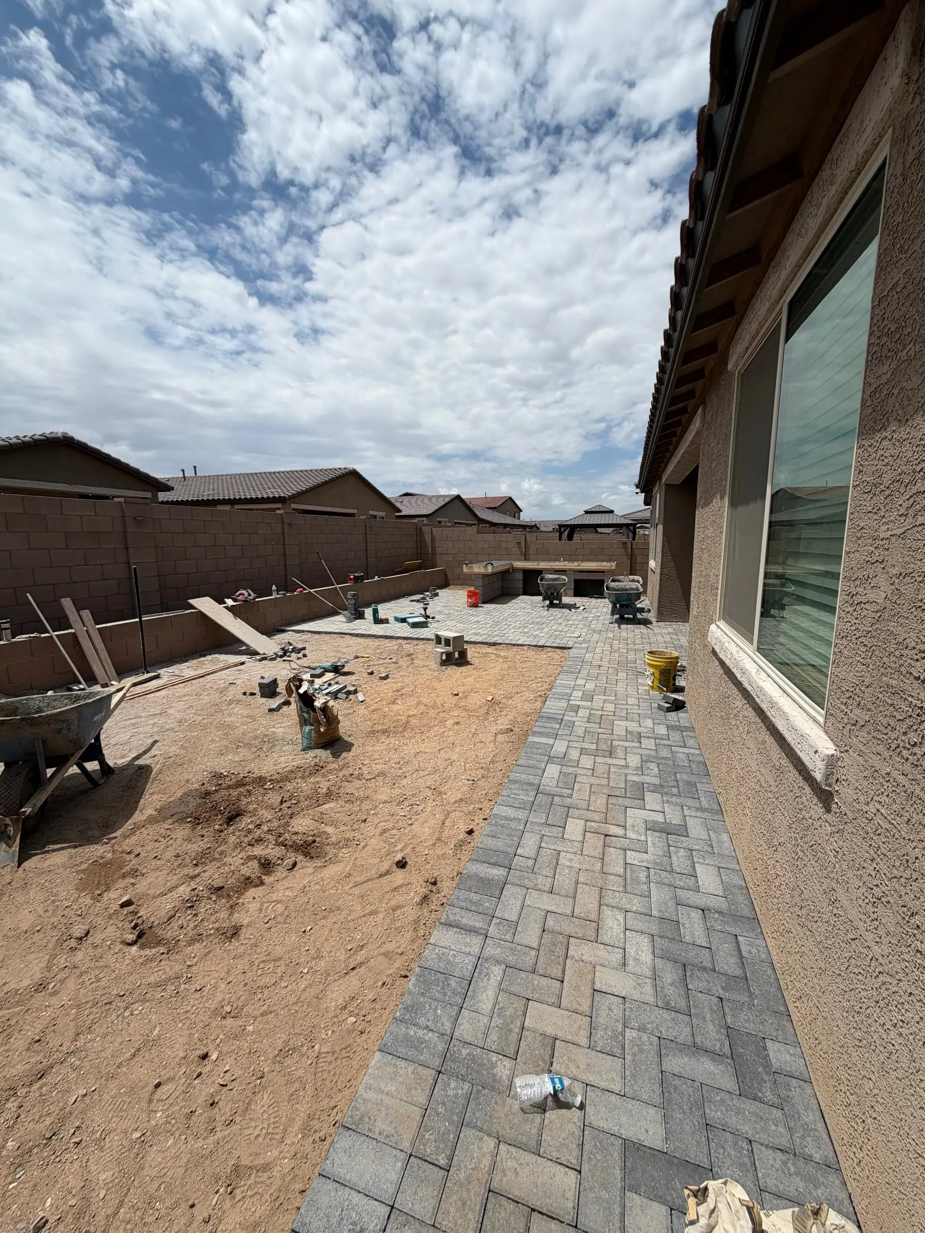 Gray herringbone paver walkway being installed along the side of a new home