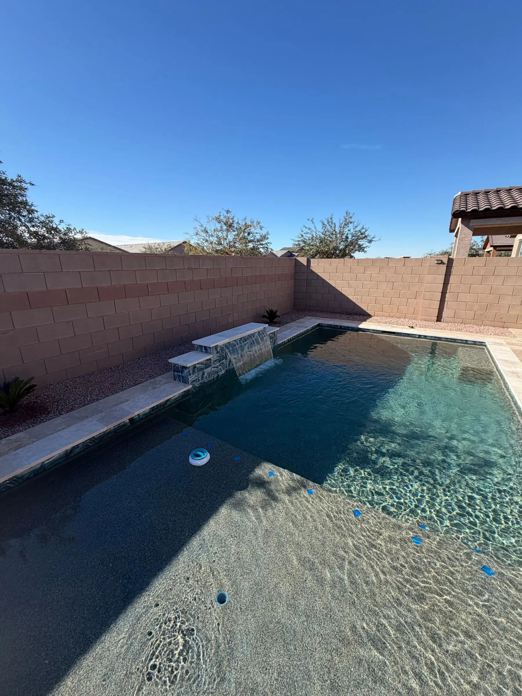 Long rectangular pool with a tiled raised wall and sheer descent spilling into it