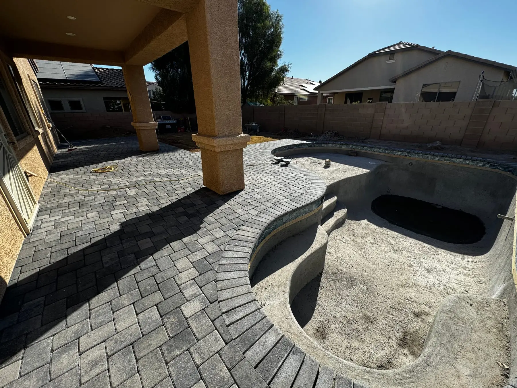 New paver deck from the covered patio around a freeform pool and spa shell, Marana, AZ.