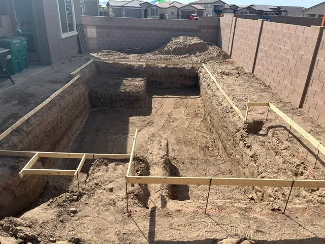Excavated rectangular pool with wood forms staked around the perimeter in a Tucson backyard.