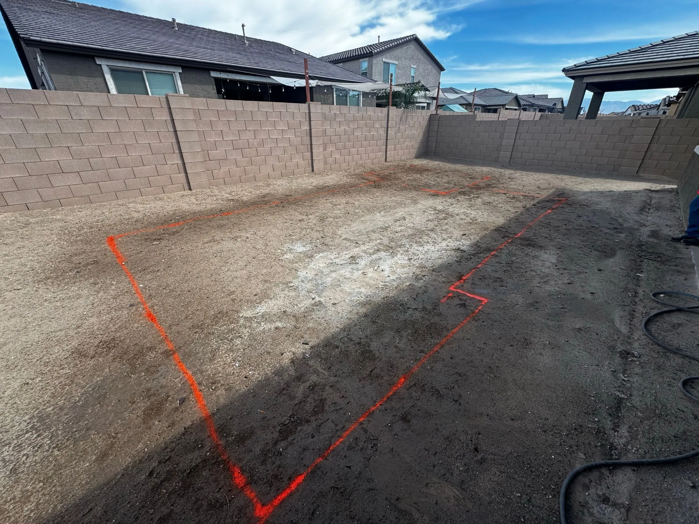 Orange marking paint outlines a new pool layout on a bare backyard lot in Marana.