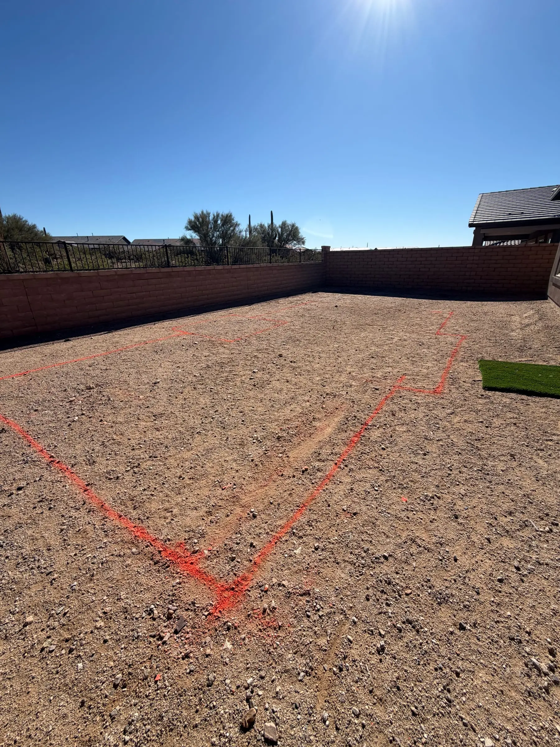Pool outline painted in orange on a gravel backyard in Marana.