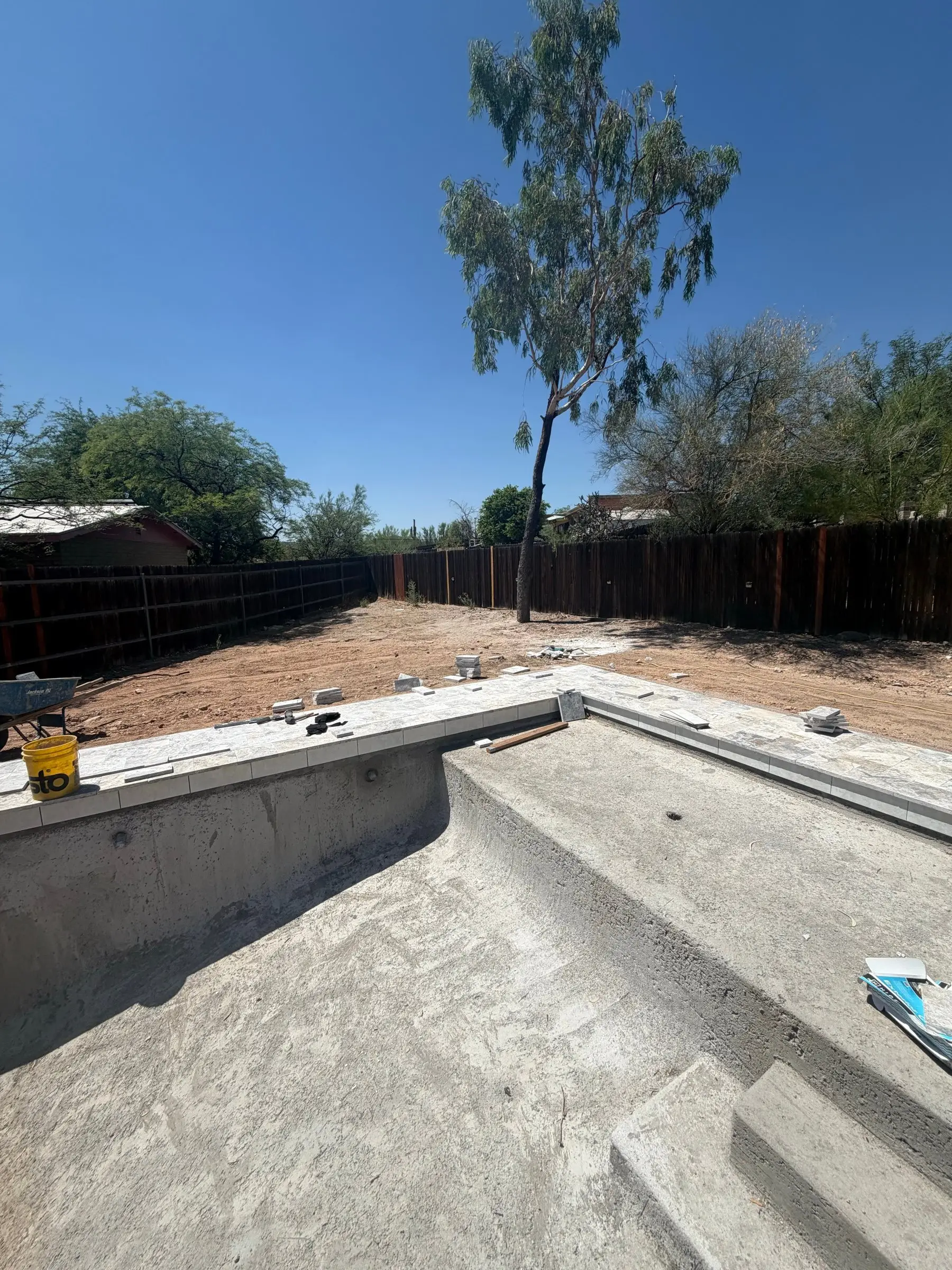 Unplastered pool shell with silver travertine coping and deck set around the steps in Tucson