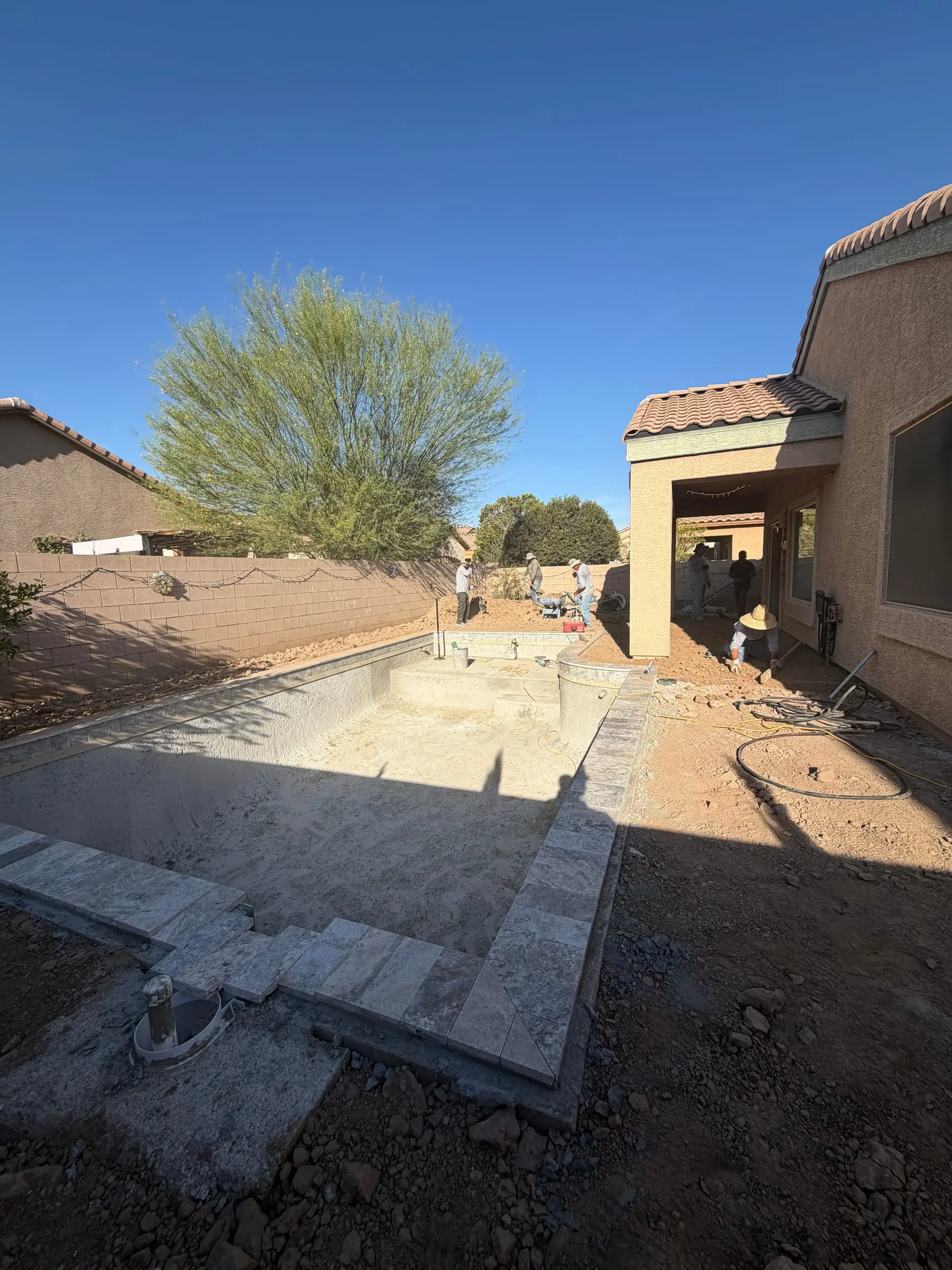 Travertine coping being set around a new rectangular pool shell, Marana, AZ.