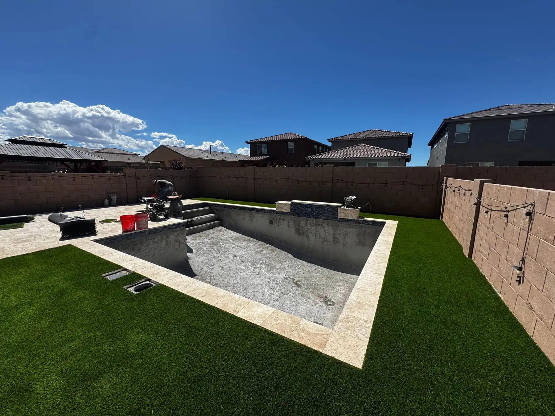 Pool shell with travertine coping set and new turf laid around it.