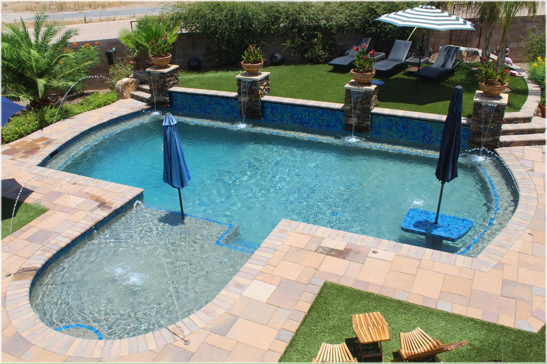 Overhead view of a pool with tanning ledge bubblers, laminar jets, glass tile wall and stone scuppers.