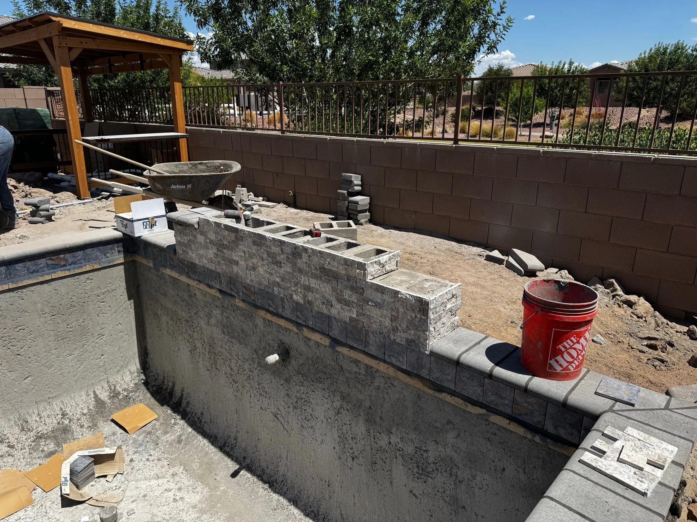 Concrete block raised wall being built along the edge of a gunite pool shell.