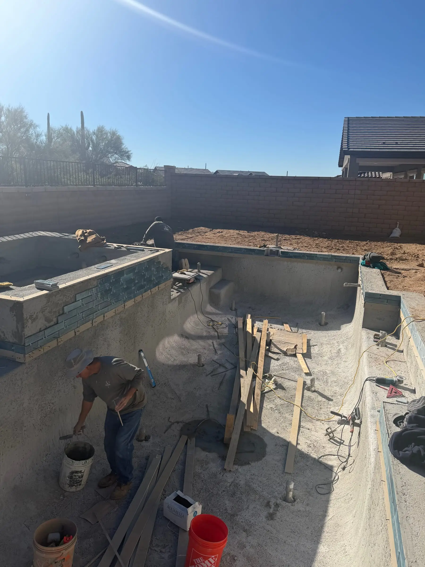 Our crew working inside a new pool shell as the raised spa gets its tile.