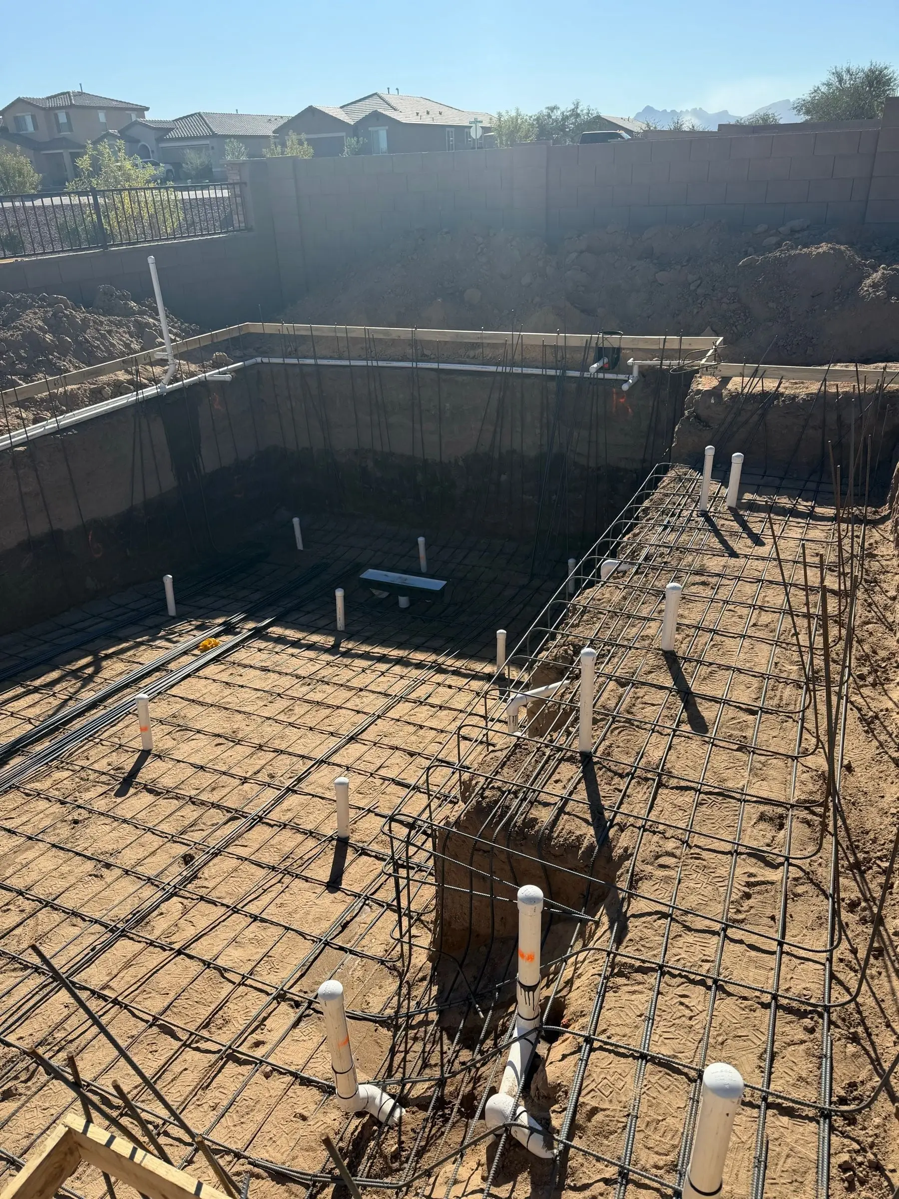 Rebar tied along the walls and floor of a deep rectangular pool excavation.
