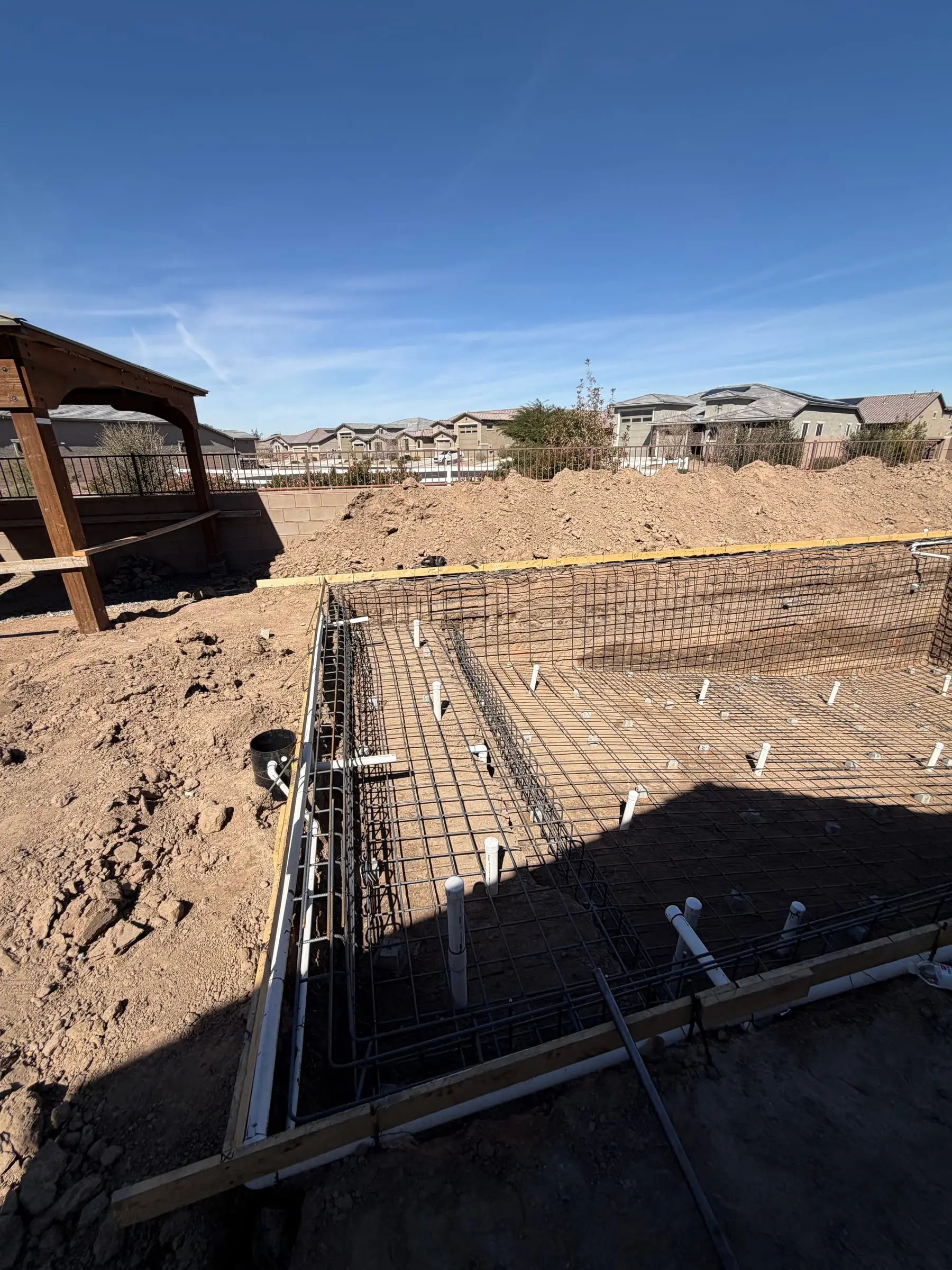 Rebar cage and plumbing stubs set in a rectangular pool excavation in Gladden Farms.