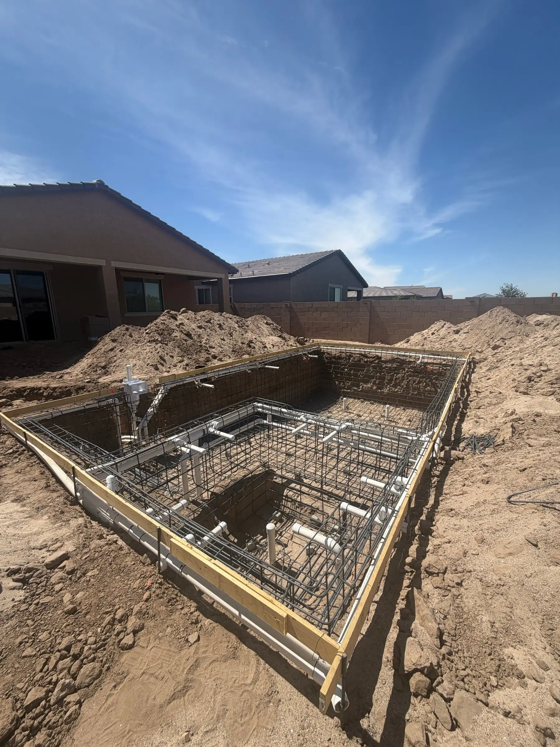 Steel rebar cage for a pool and attached spa inside a fresh excavation