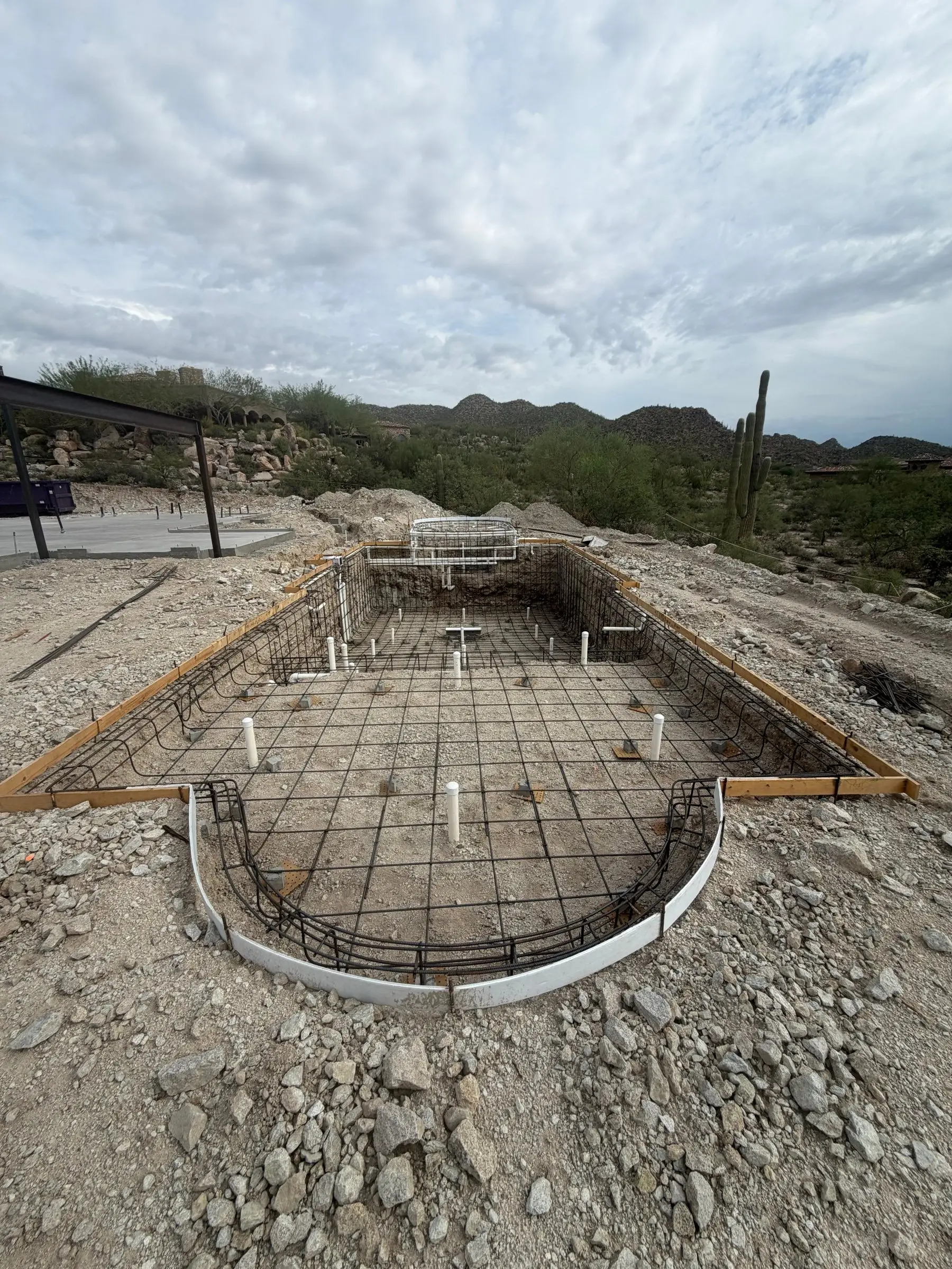Rebar and plumbing for a rectangular pool with a curved spa end in rocky desert