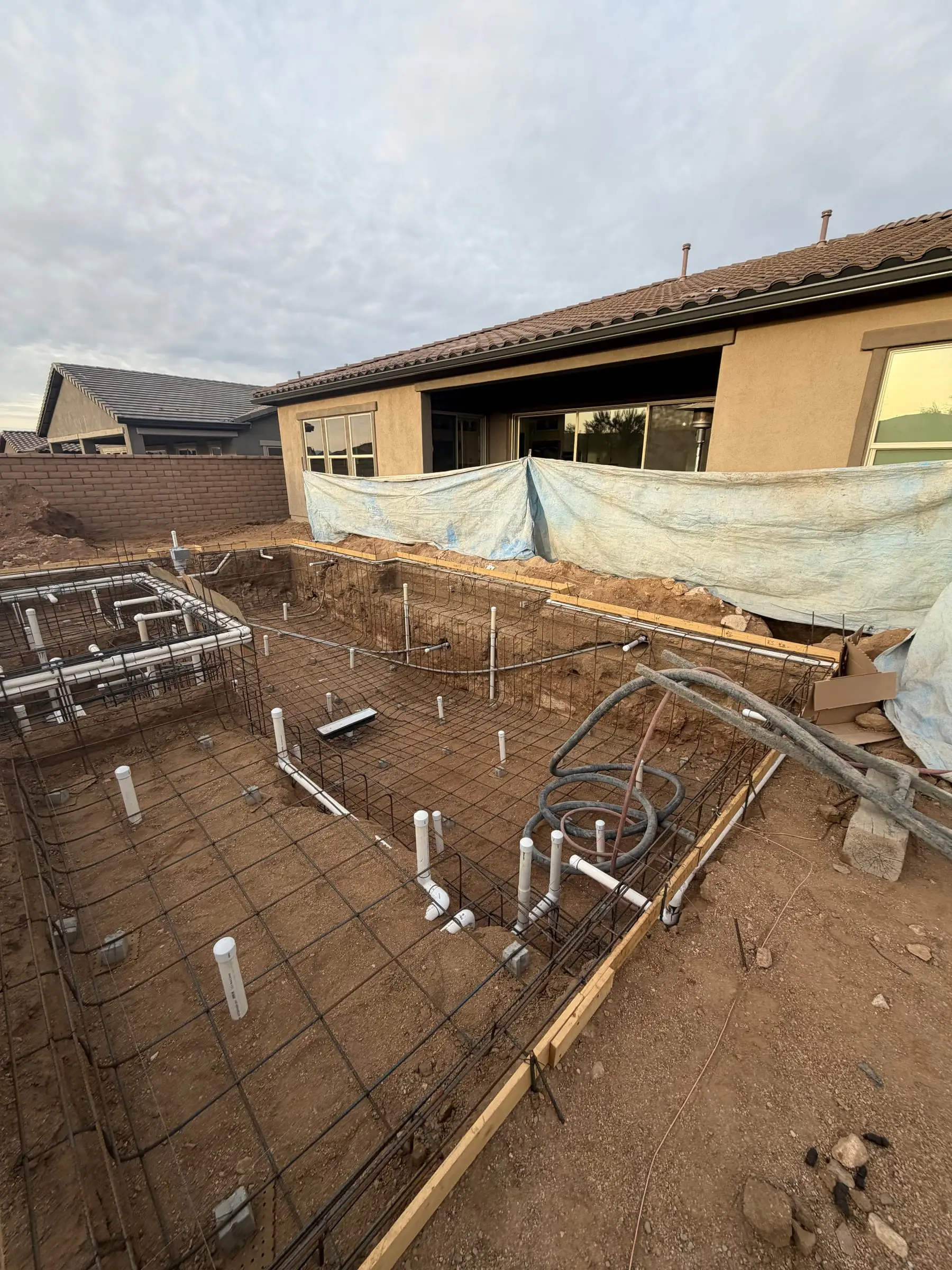 Rebar grid and plumbing stubs for a pool and raised spa inside wood forms.