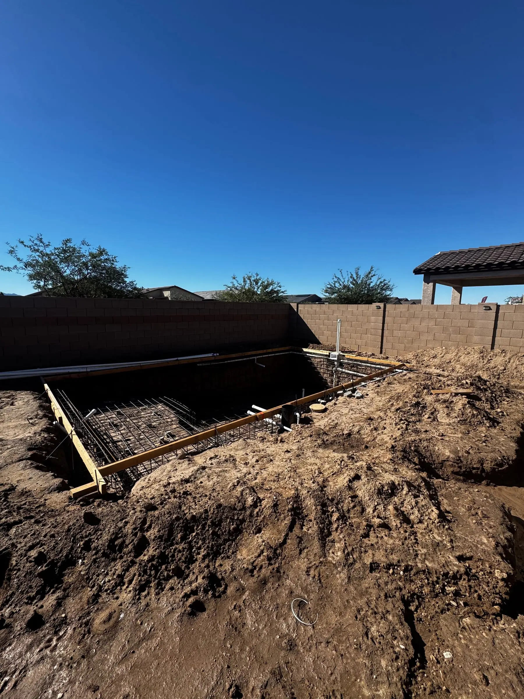 Rebar grid tied across a rectangular pool excavation beside a block wall in Marana.