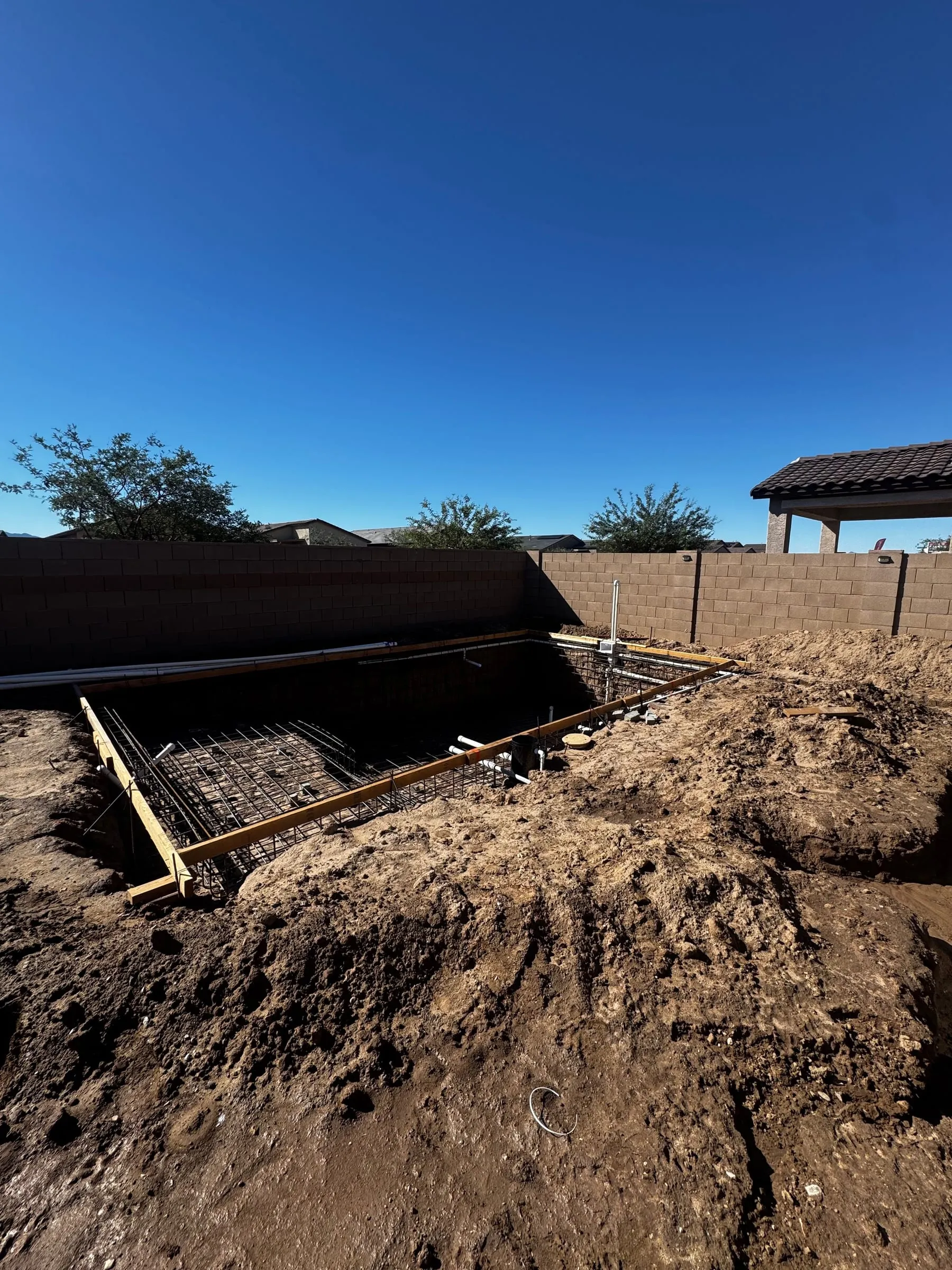 Rebar grid in a pool excavation next to a perimeter block wall that forms part of the pool barrier, Marana.