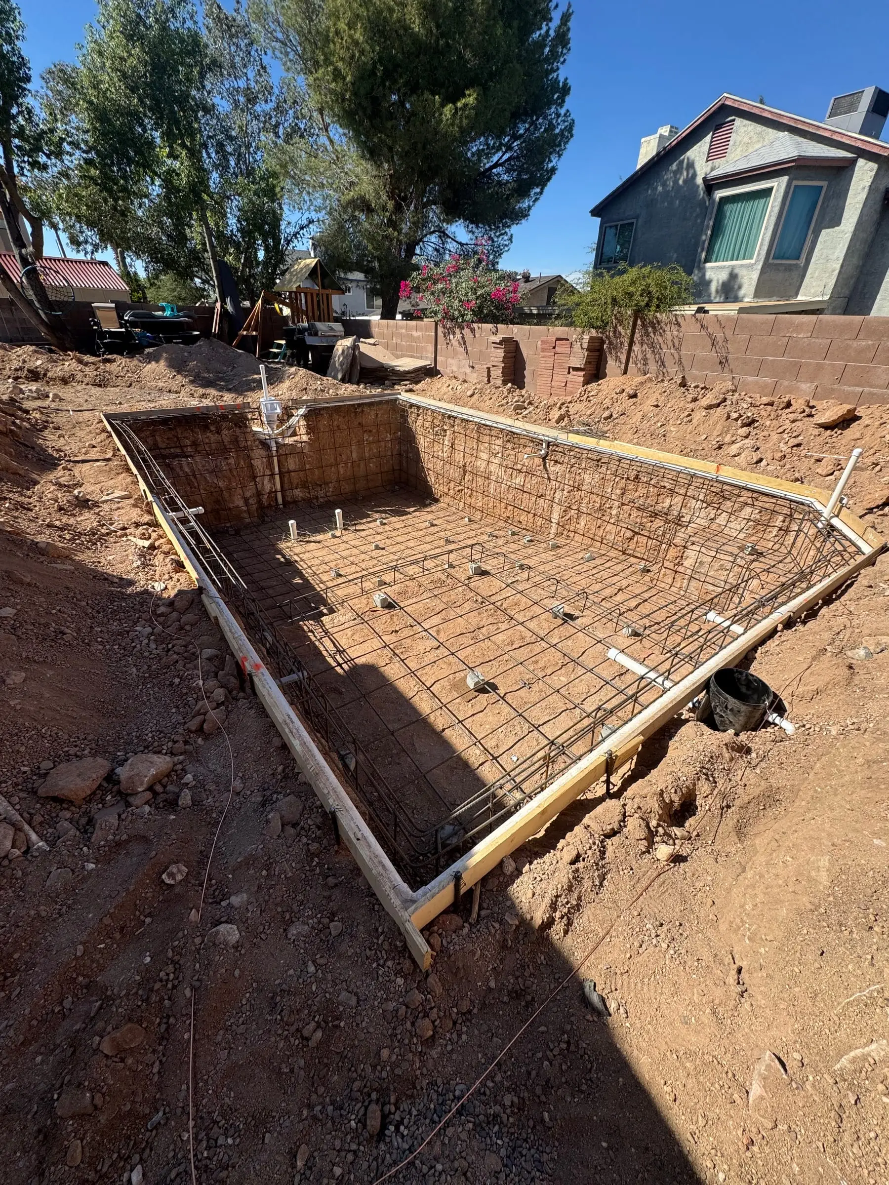 Rebar grid tied inside a rectangular pool excavation with wood forms.