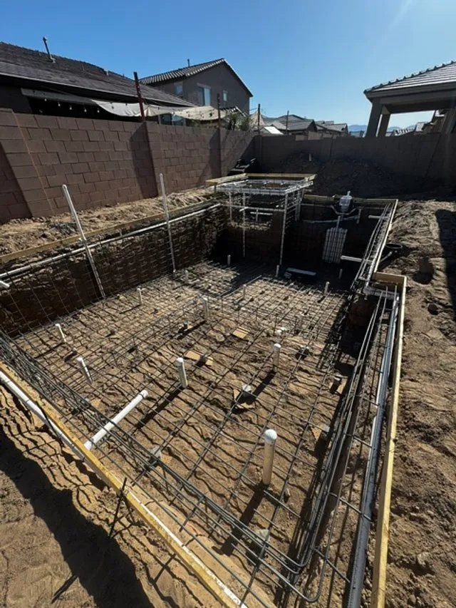 Steel rebar grid and plumbing lines set in an excavated pool and spa before shotcrete.