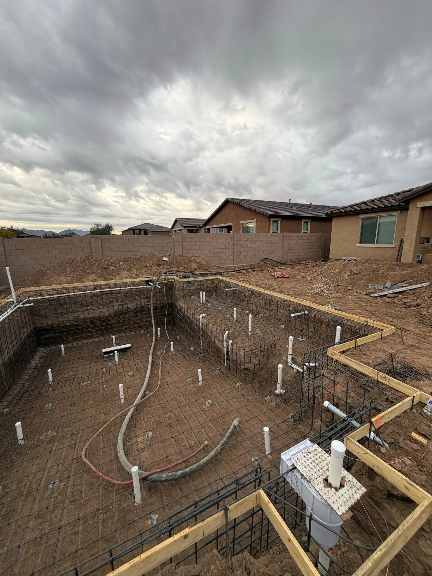 Rebar grid and plumbing lines set in a rectangular pool excavation with wood forms, Marana, AZ.