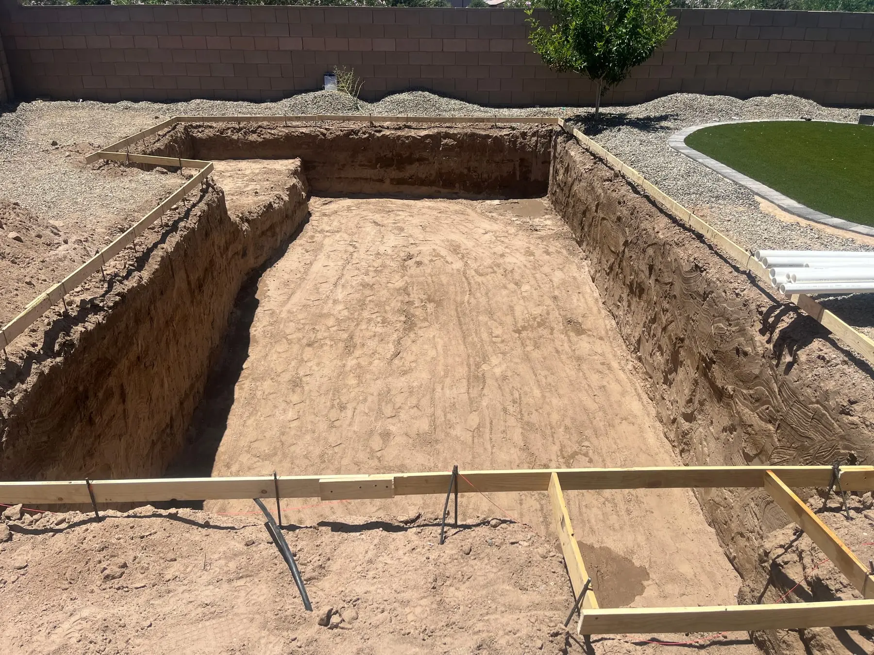 Rectangular pool excavation with wood forms beside existing turf, Gladden Farms in Marana, AZ.