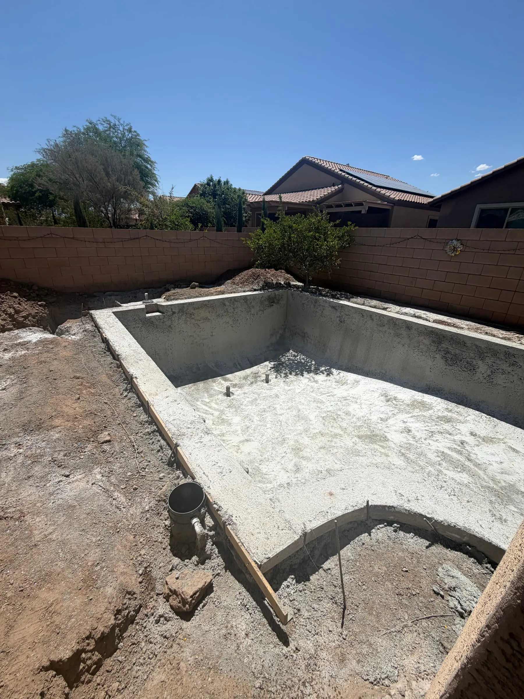 Rectangular shotcrete pool shell with steps in a backyard under construction, Marana, AZ.