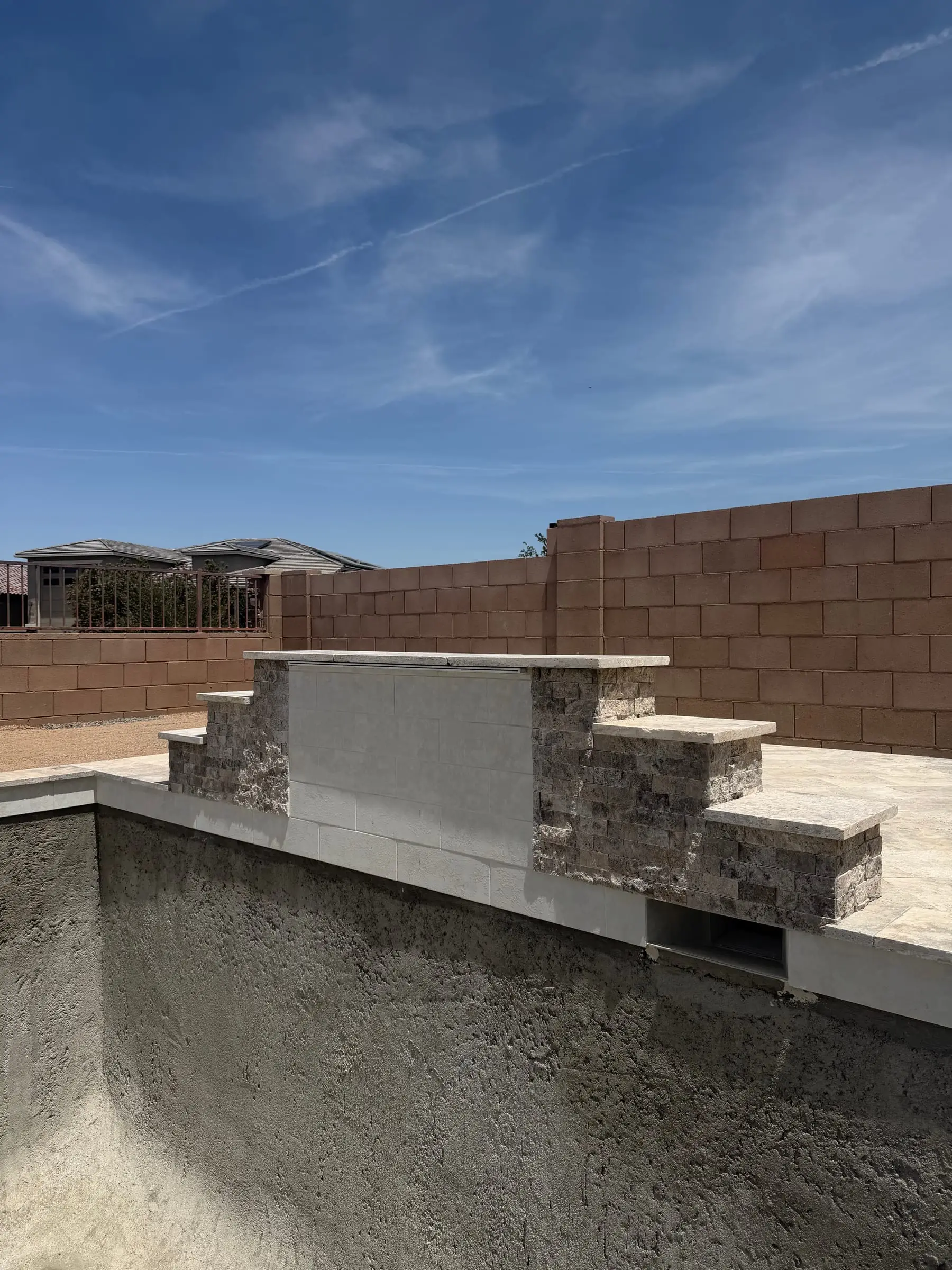 Shotcrete pool shell with a stacked stone raised wall and travertine cap taking shape, Gladden Farms in Marana, AZ.