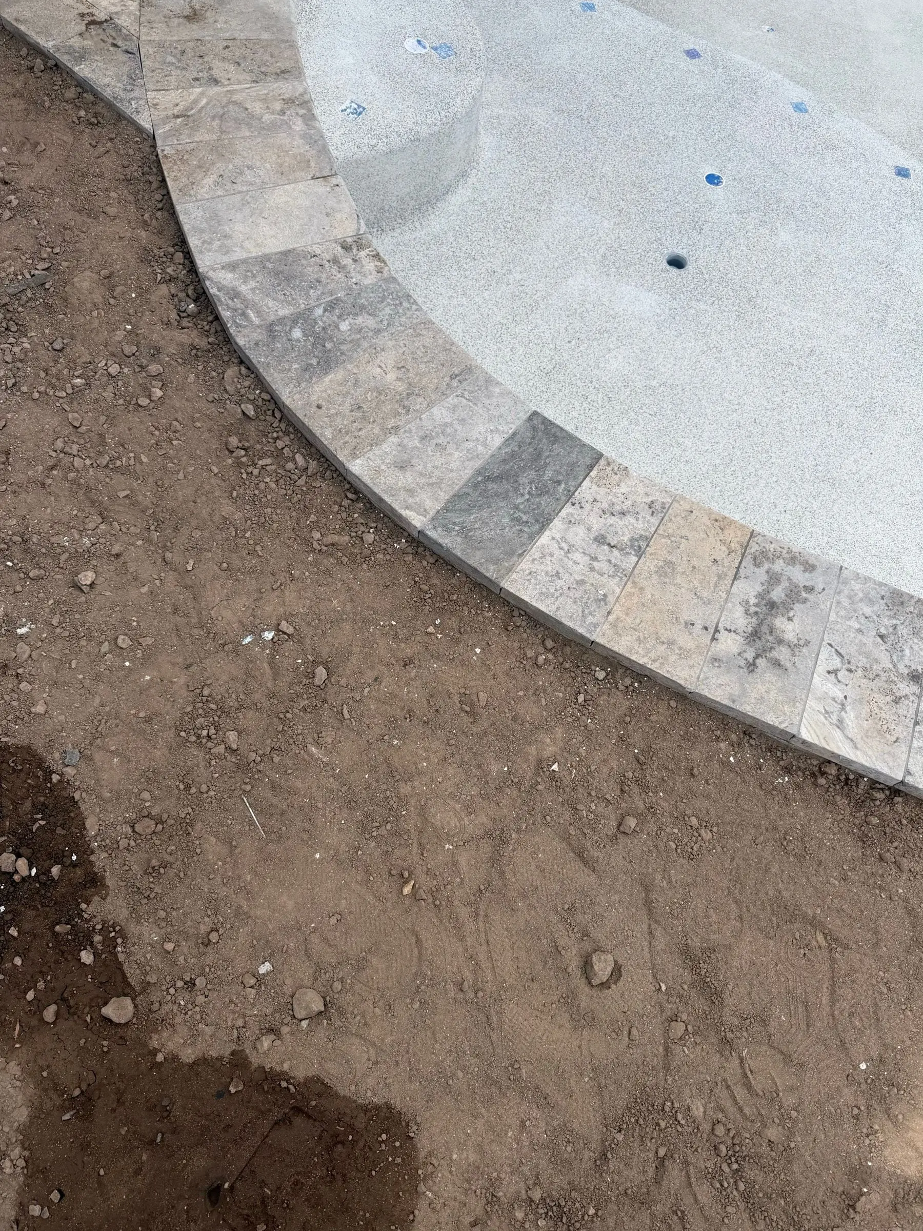 Close view of travertine coping curving along the edge of a newly plastered pool, Marana, AZ.