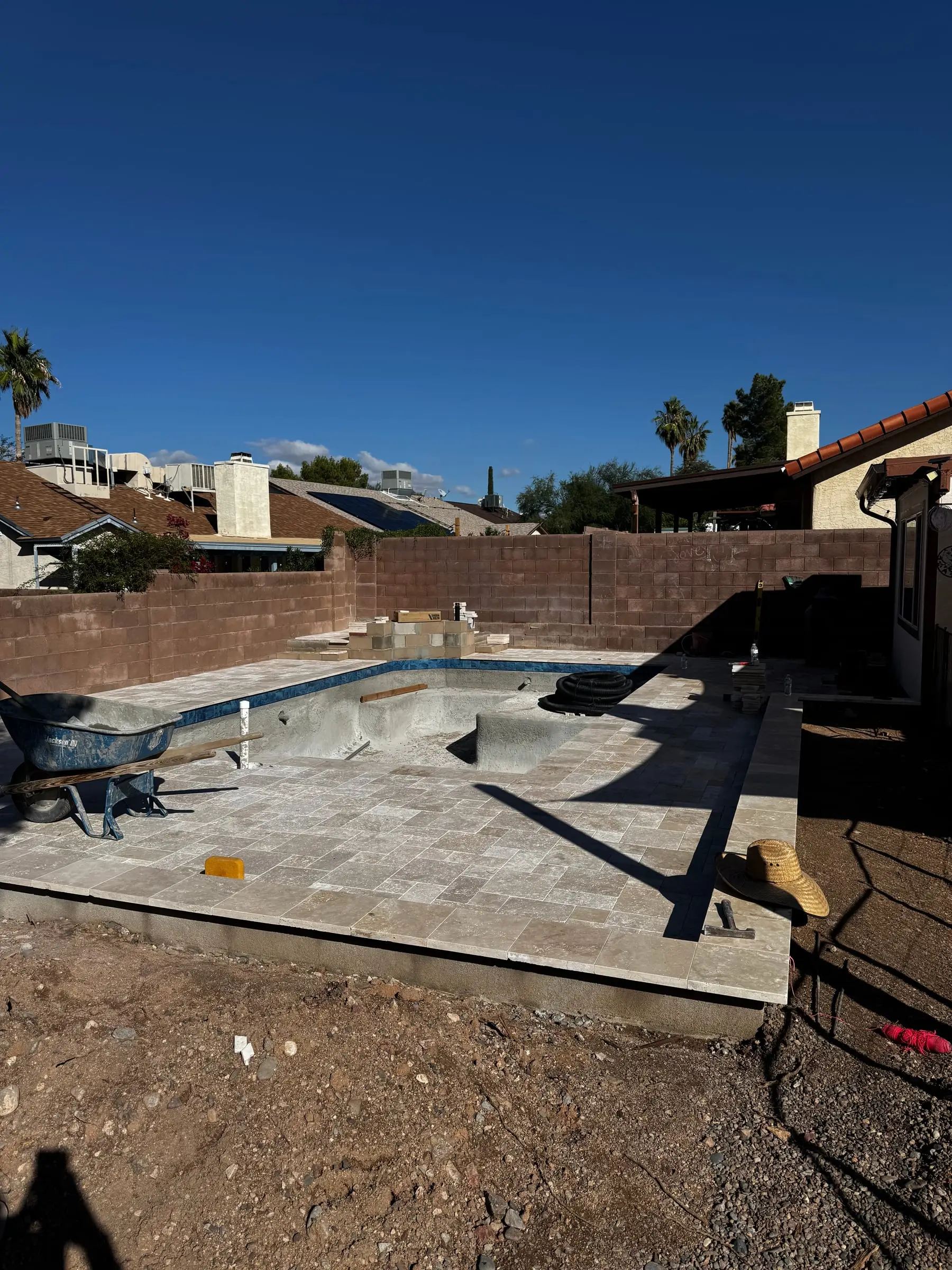 Travertine coping and deck going in around a new pool shell.