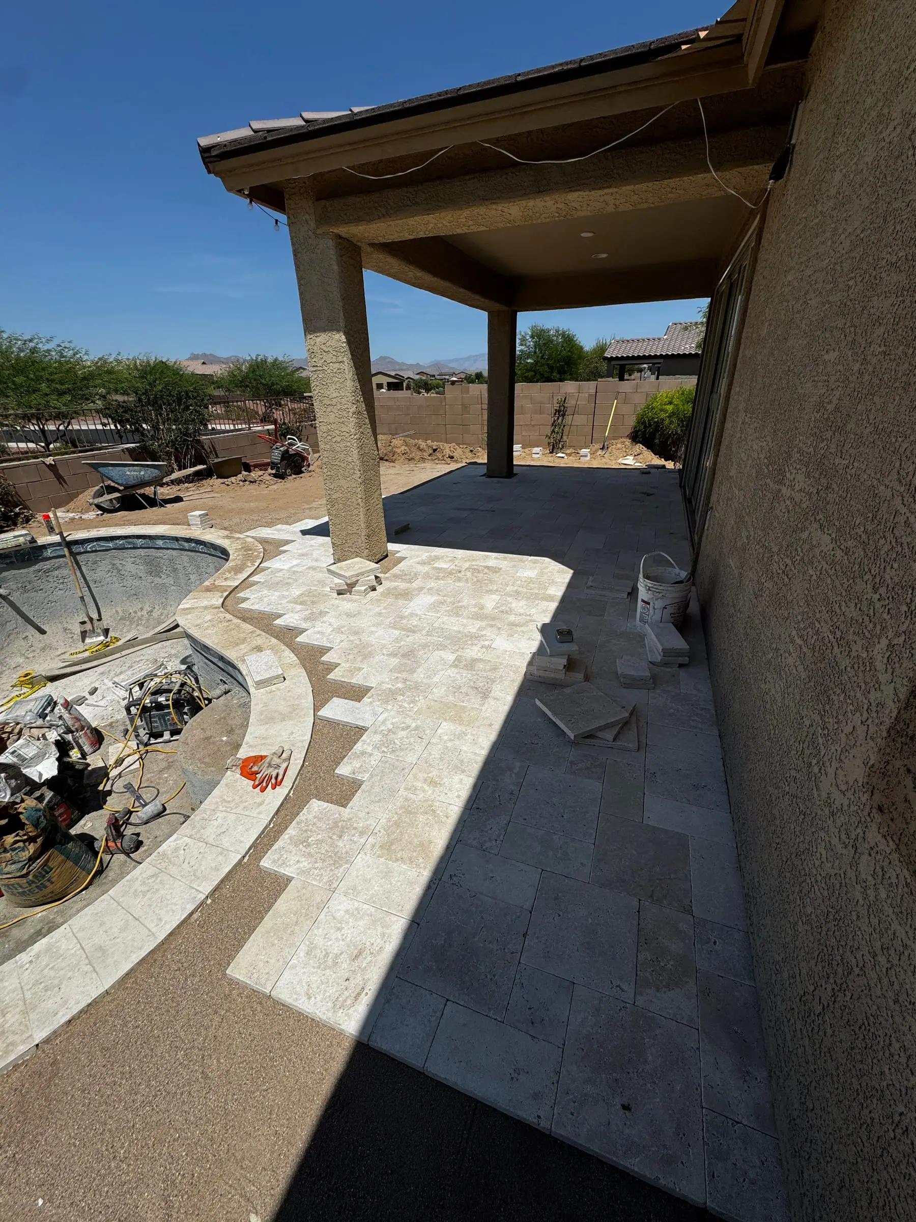 Travertine deck going in from the covered patio around a freeform pool, Marana, AZ.