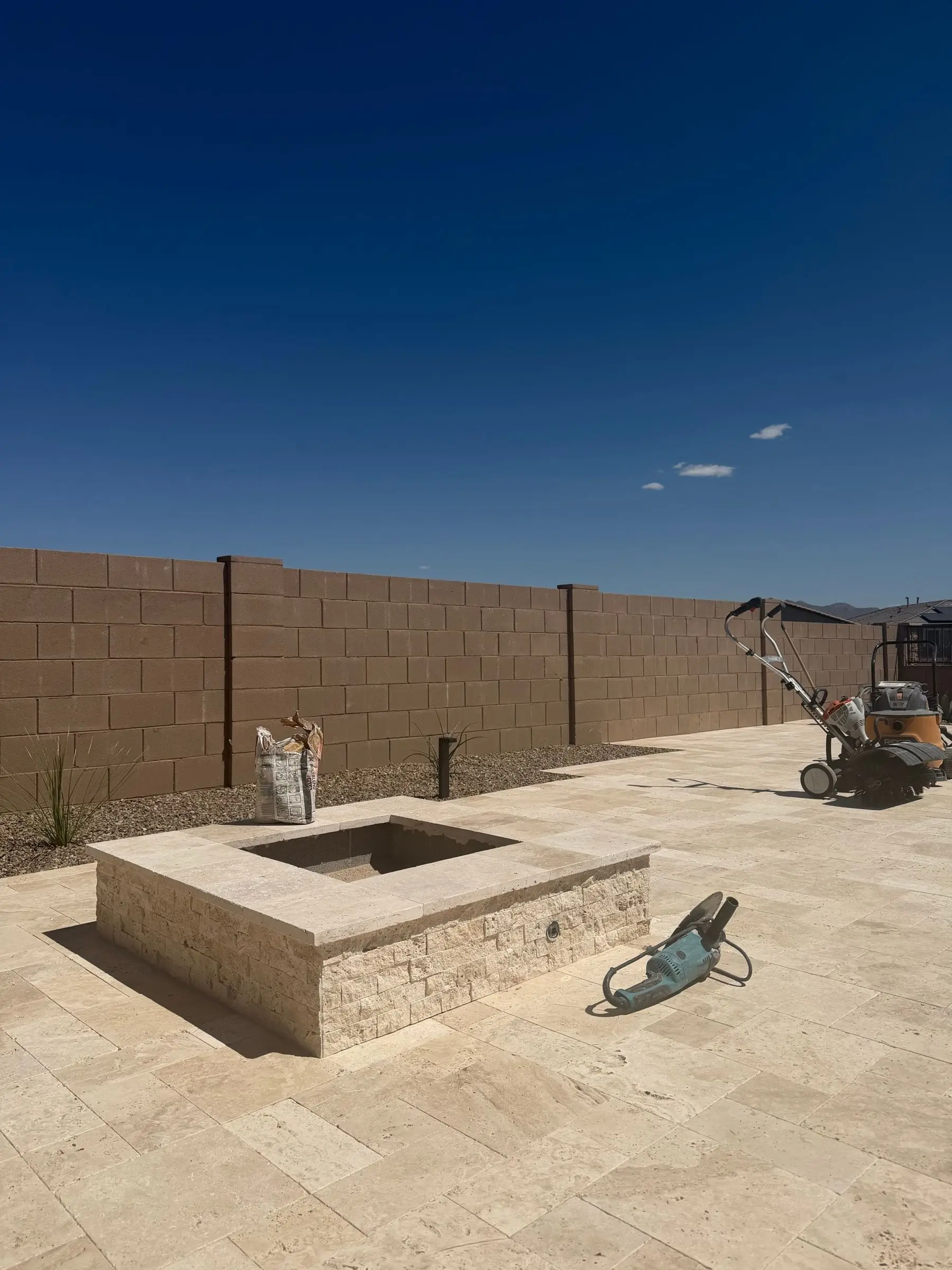 Square fire pit clad in travertine on a new travertine paver patio, Marana, AZ.