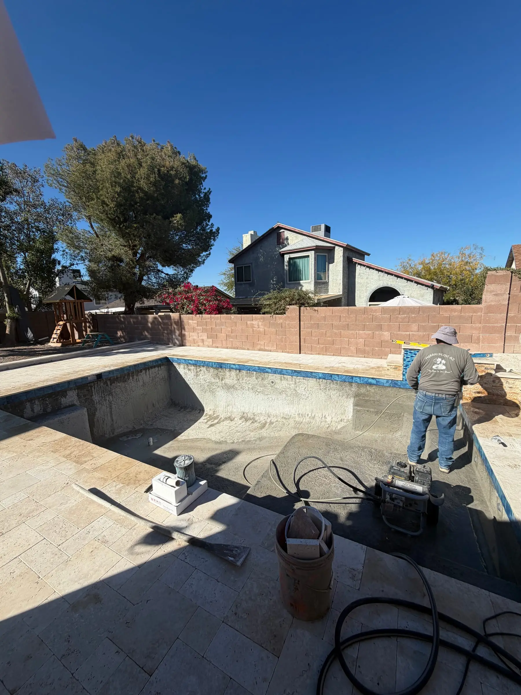 Waterline tile set around a pool shell with a finished travertine deck.